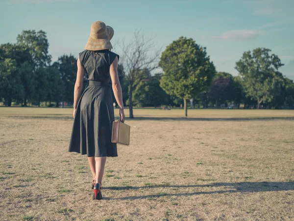 Elegante vrouw wandelen in het park met werkmap — Stockfoto