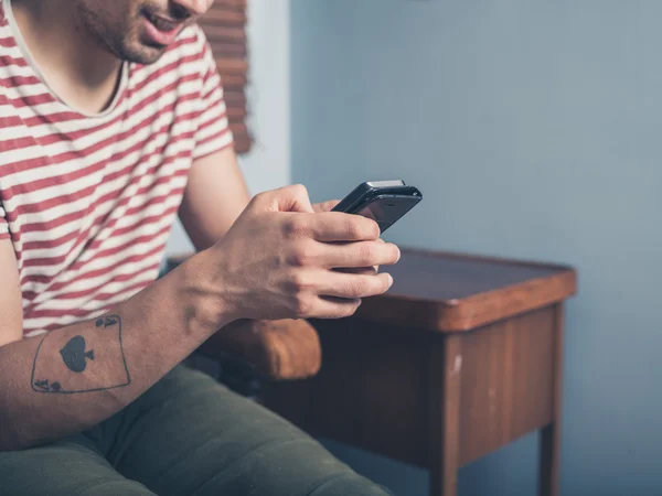 Jovem usando telefone inteligente em casa — Fotografia de Stock