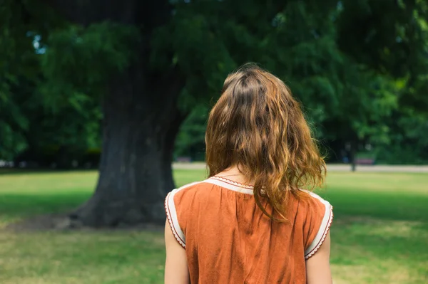 Jovem mulher olhando para a árvore no parque — Fotografia de Stock