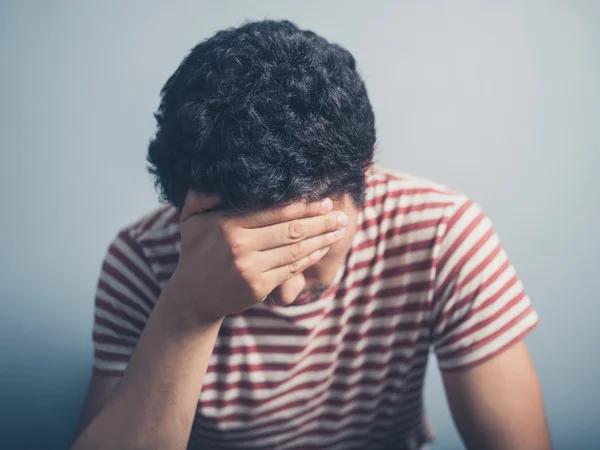 Sad young man with hand on forehead — Stock Photo, Image