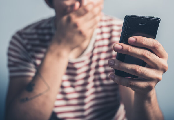 Шокированный человек со смартфоном
