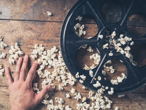 Mão com rolo de filme e pipoca — Fotografia de Stock