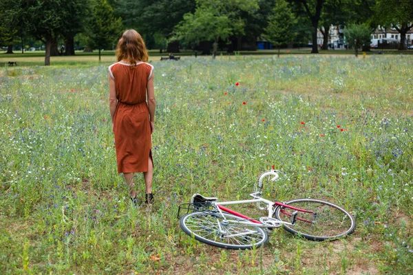 Young woman in park with bicycle — Stock Photo, Image