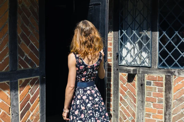 Jovem mulher abrindo porta e entrando em prédio antigo — Fotografia de Stock