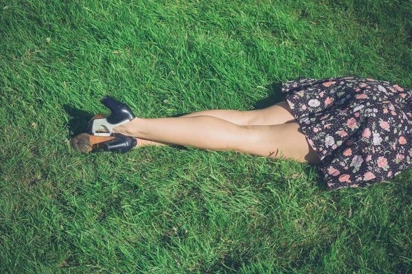 Nogi młoda kobieta, leżąc na trawie w dziedzinie — Zdjęcie stockowe