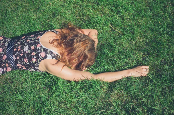 Jonge vrouw liggen in het gras op een zomerdag — Stockfoto