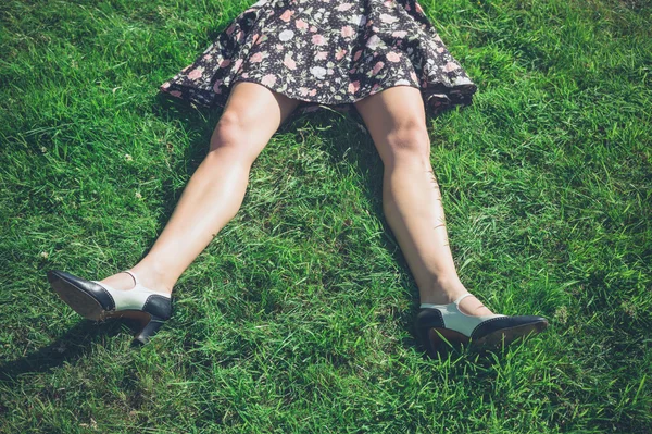 Benen van jonge vrouw liggen op gras in veld — Stockfoto