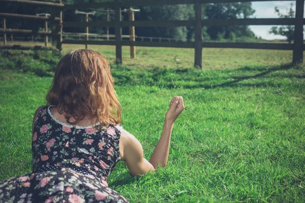 Jonge vrouw liggen in het gras op een zomerdag — Stockfoto