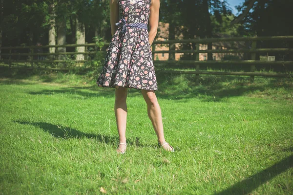 Молодая женщина, стоящая в поле у забора в летний день — стоковое фото