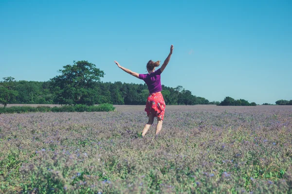 Feliz joven saltando en el campo de flores púrpuras —  Fotos de Stock