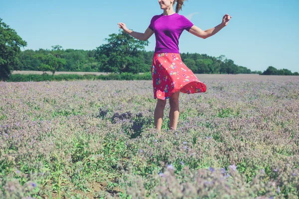 Feliz joven mujer girando en el campo de flores púrpuras —  Fotos de Stock