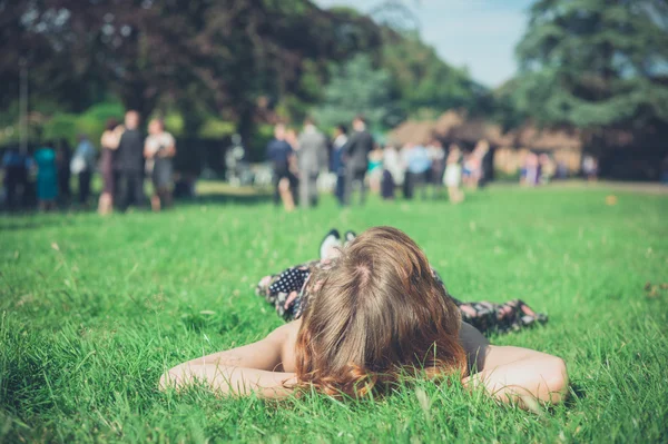 Vrouw ontspannen op gras op feestje — Stockfoto