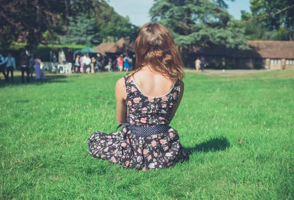 Vrouw ontspannen op gras op feestje — Stockfoto