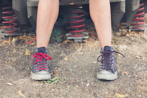 Jonge vrouw zittend op speeltoestellen buiten — Stockfoto