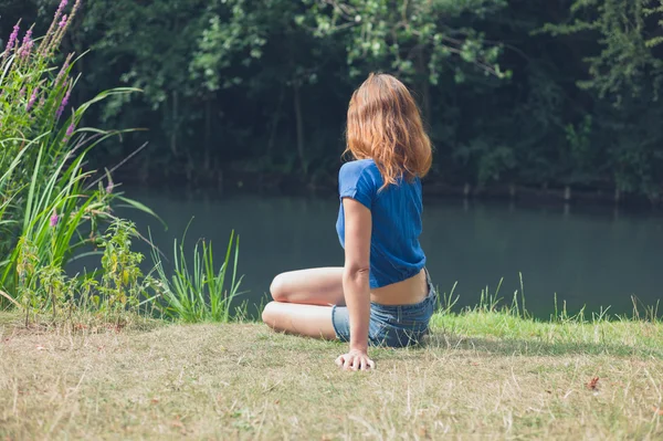 Jeune femme se relaxant au bord de l'eau dans le parc — Photo