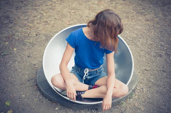 Молодая женщина сидит в большой металлической тарелке — стоковое фото