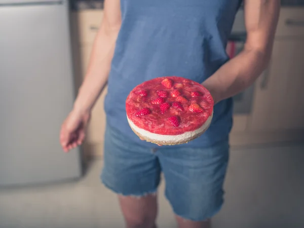 Mujer joven de pie en la cocina con un pastel —  Fotos de Stock
