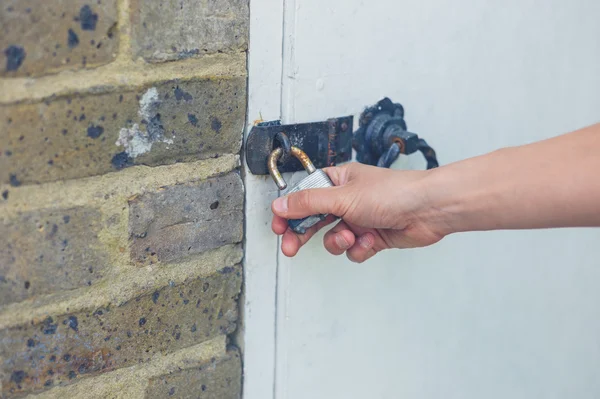 Vrouwelijke hand aanraken hangslot buiten — Stockfoto