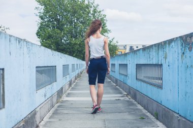 Bir yaya köprüsü üzerinde yürüyen genç kadın