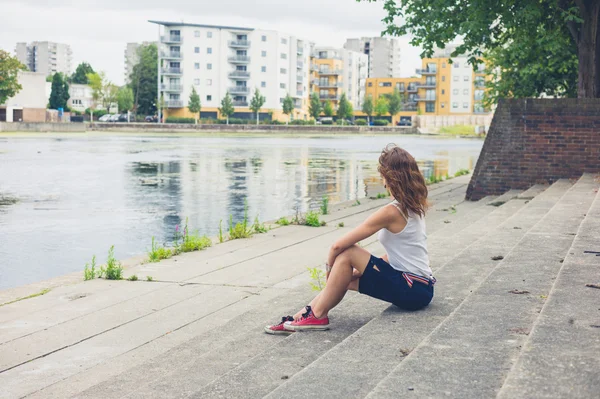 Молодая женщина сидит на ступеньках у пристани — стоковое фото