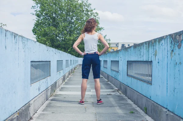 Junge Frau steht auf einer Fußgängerbrücke — Stockfoto