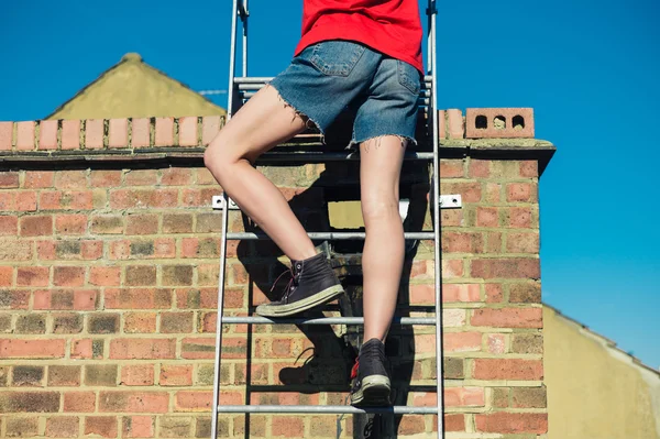 Woman climbing ladder on a roof — Stock Photo, Image