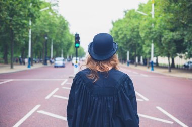 Woman in hat and graduation gown in the street clipart