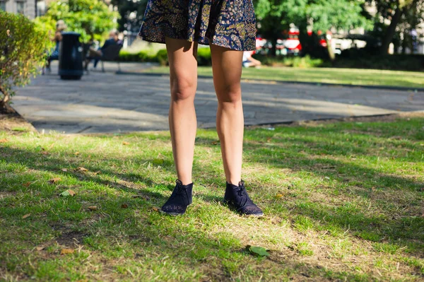 Pernas de jovem mulher em pé na grama no parque — Fotografia de Stock