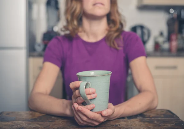 Mujer joven con taza en la cocina — Foto de Stock