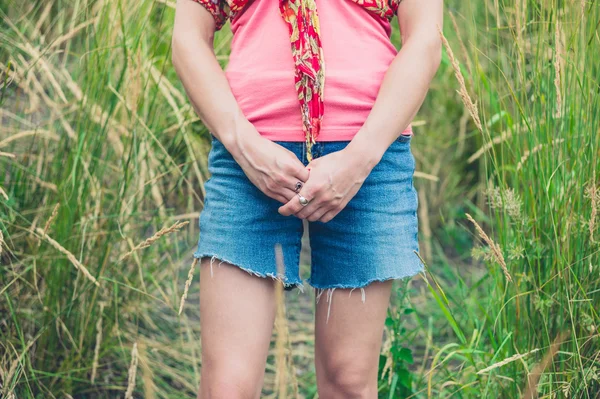 Junge Frau steht im hohen Gras — Stockfoto