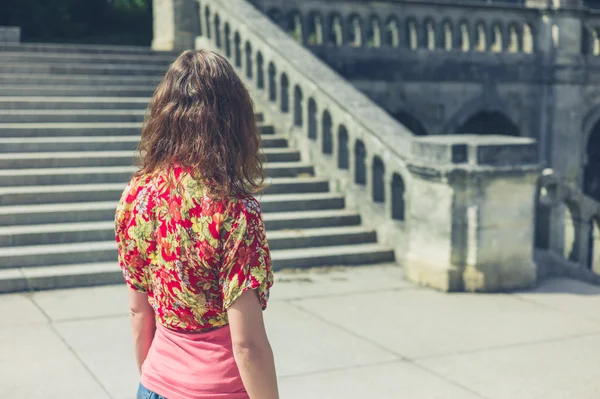 Jonge vrouw permanent door stappen van oude gebouw — Stockfoto