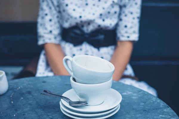 Donna a tavola con tazze di caffè vuote — Foto Stock