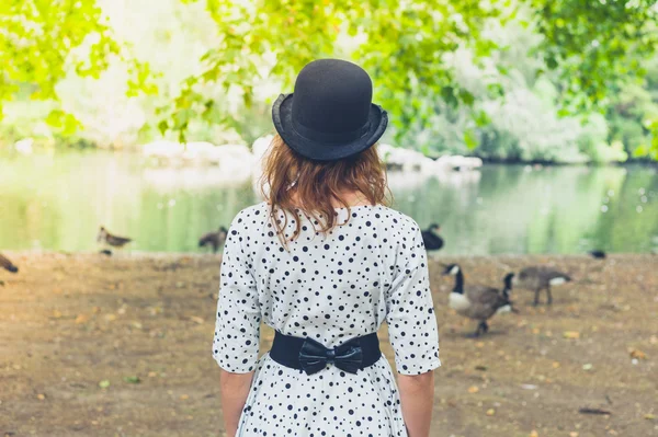 Mujer en sombrero de jugador de bolos por estanque en el parque — Foto de Stock