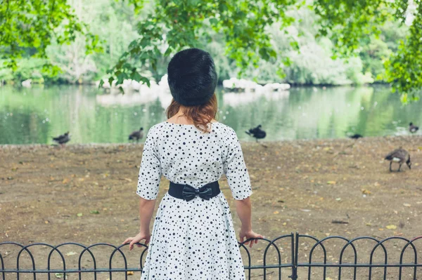 Woman wearing fur hat by pond in park — Stock Photo, Image