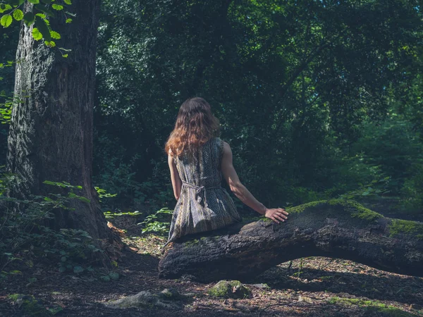 Žena sedící na kládě v lese — Stock fotografie