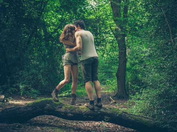 Jeune couple debout sur bûche baisers — Photo