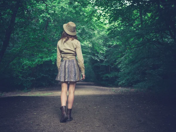 Jonge vrouw lopen op weg in bos — Stockfoto