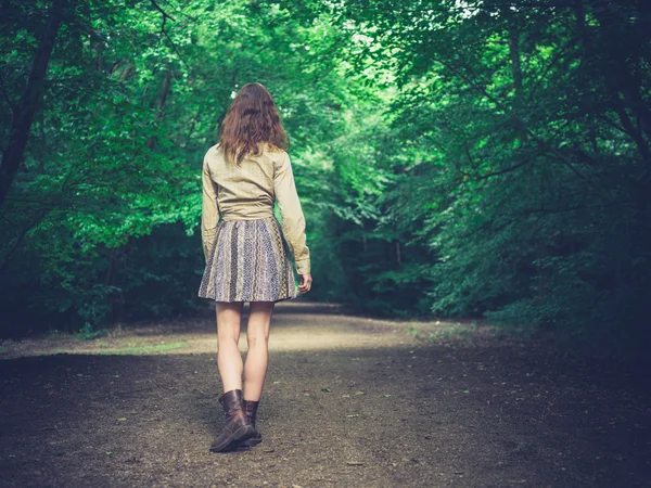 Jovem mulher caminhando na estrada na floresta — Fotografia de Stock