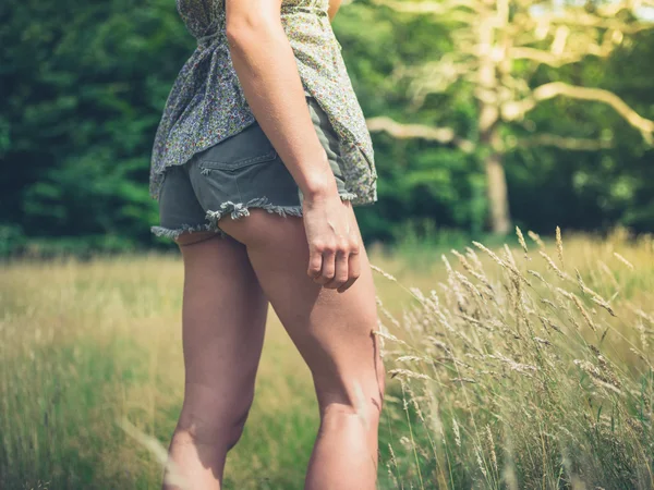 Young woman standing in meadow on sunny day — Stock Photo, Image