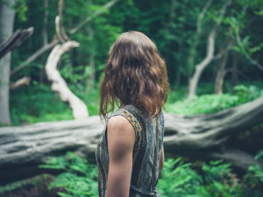 Ormanda düşmüş ağaç tarafından duran genç kadın