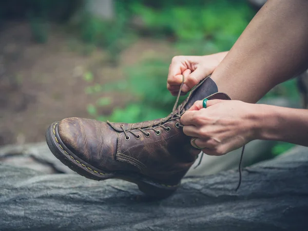 Genç kadın tyoing ormandaki onun botları — Stok fotoğraf