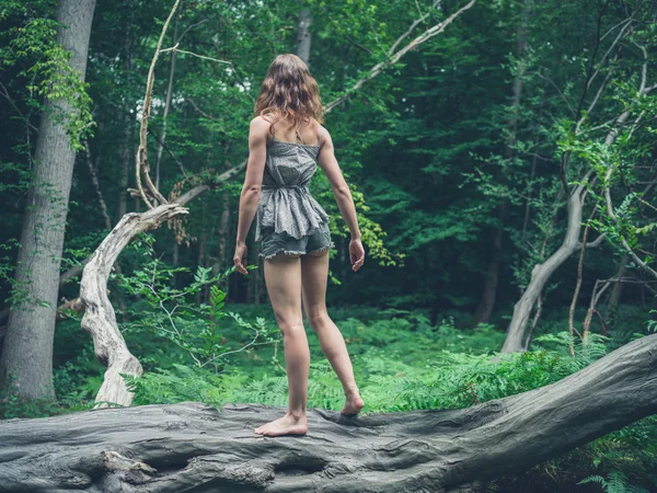 Barefoot woman standing on a fallen tree in the forest — Stock Photo, Image