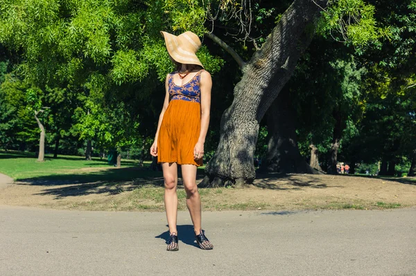 Junge Frau mit Hut steht im Park — Stockfoto