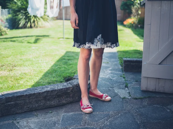 Junge Frau steht an einem Schuppen im Garten — Stockfoto