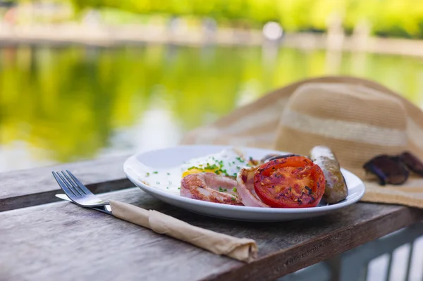 Sombrero y desayuno junto a un estanque en el parque — Foto de Stock