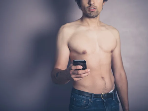 Молодой мужчина без рубашки со смартфоном — стоковое фото