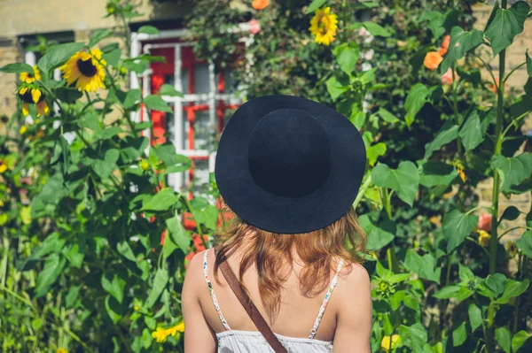 Frau mit Hut schaut Sonnenblumen an — Stockfoto