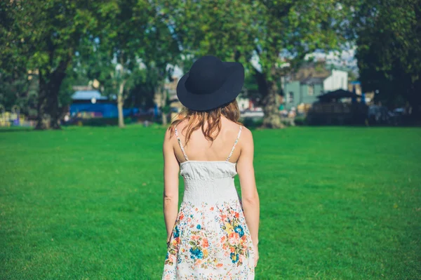 Jonge vrouw met hoed staande in park — Stockfoto