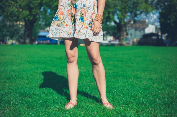 Mulher de vestido em pé na grama no parque — Fotografia de Stock