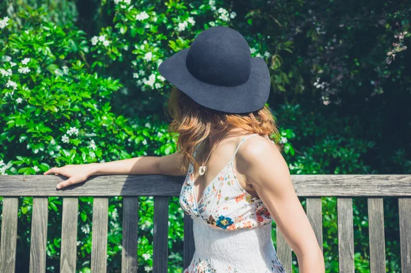 Jeune femme avec chapeau sur banc dans le parc — Photo